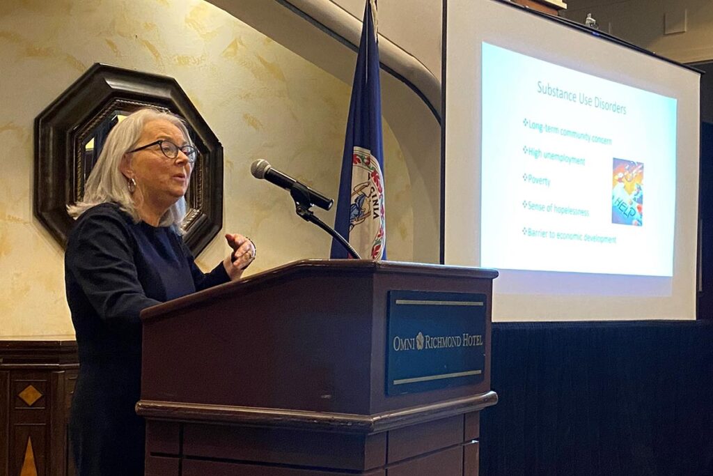 Sharon Buckman at a podium, speaking on Substance Use Disorder.